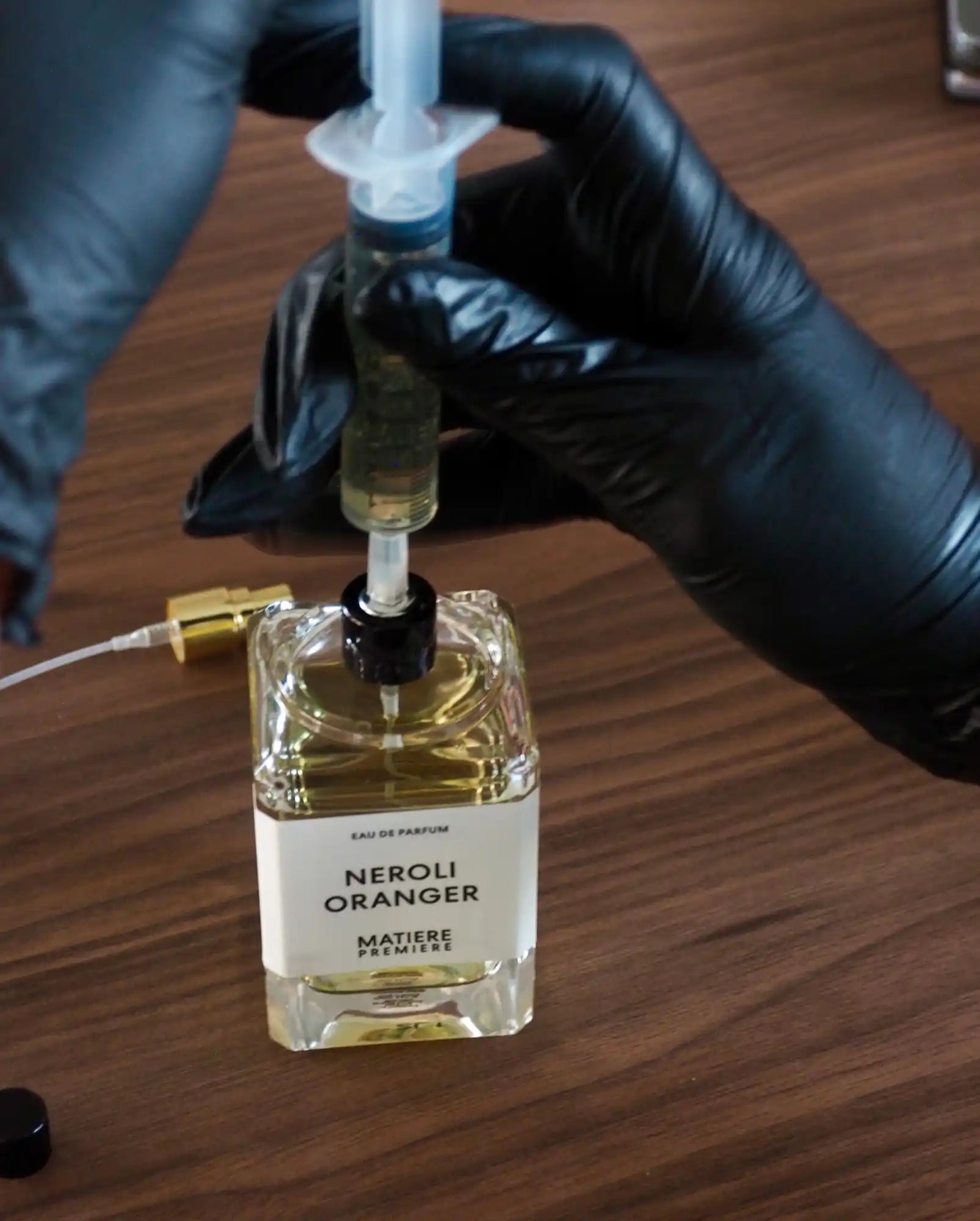 Une bouteille de parfum en train d'être reconstituée avec une seringue.
