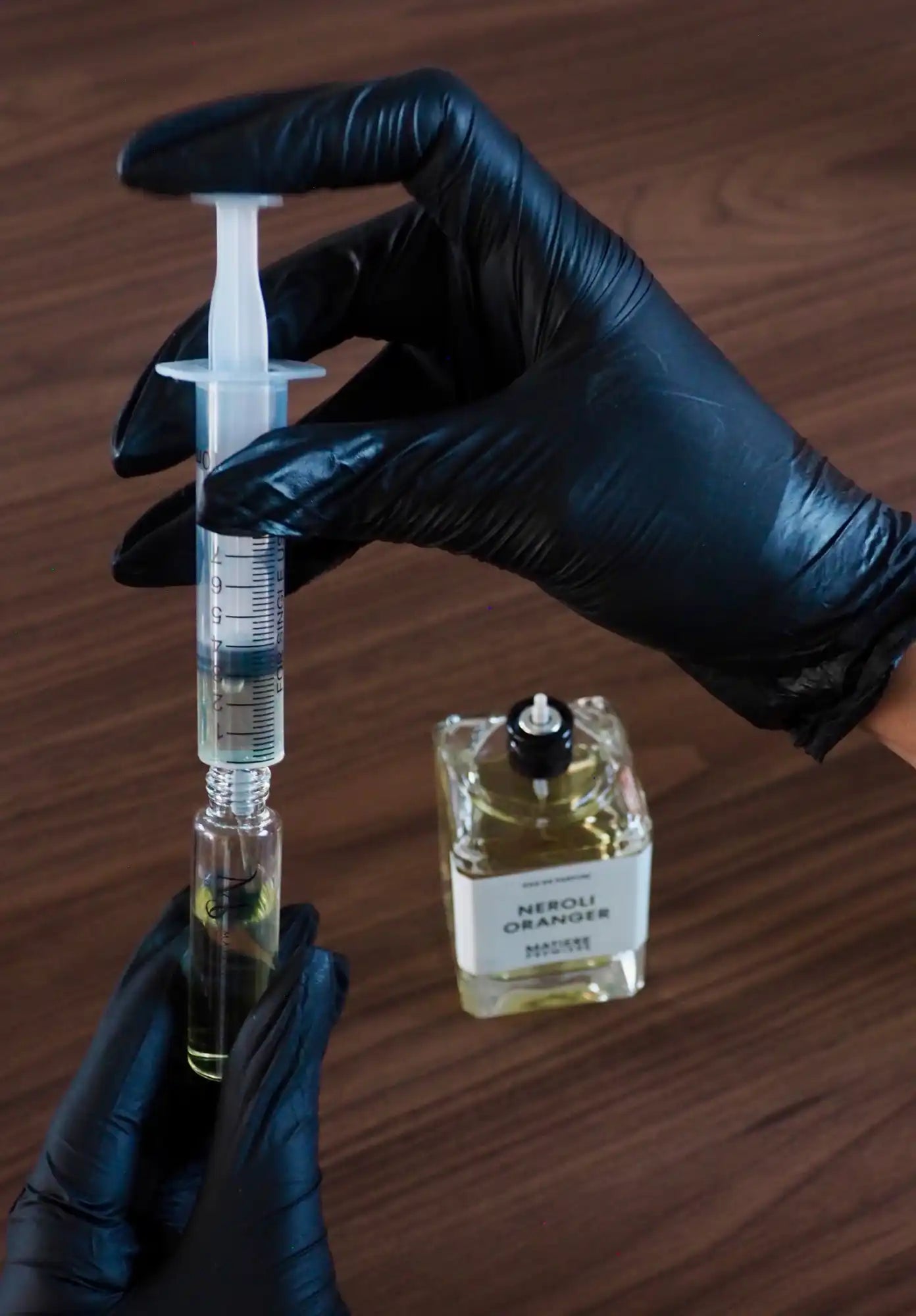 Parfum étant versé dans un flacon de voyage de taille réduite.